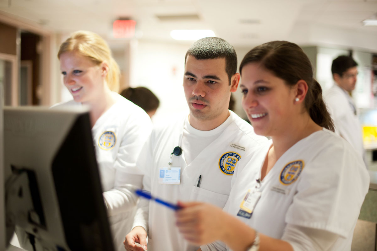 diverse group of individuals in white lab coats at the University of Rochester Medical Center, engaged in collaborative work.