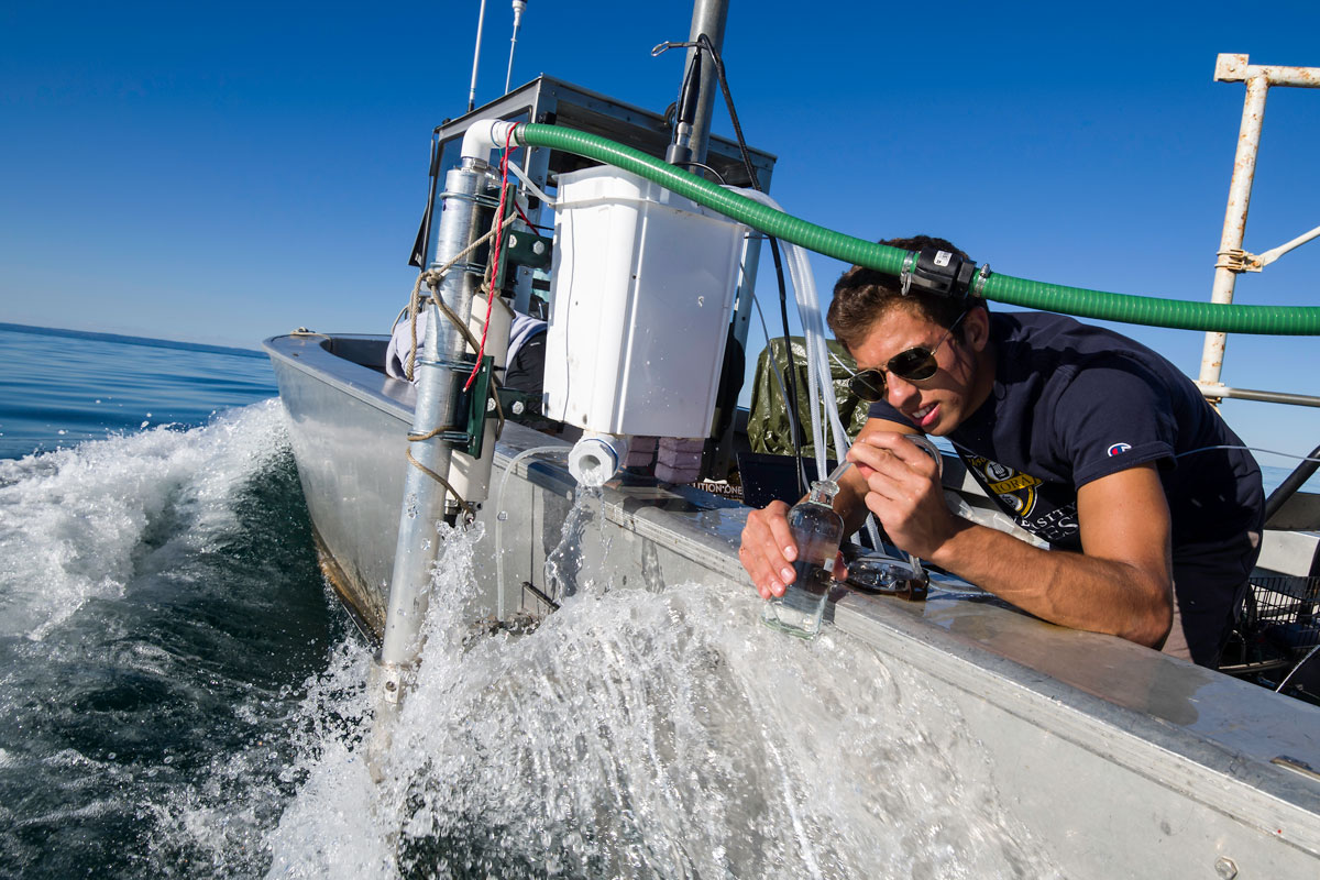 A man gathering water samples for the University of Rochester research program.