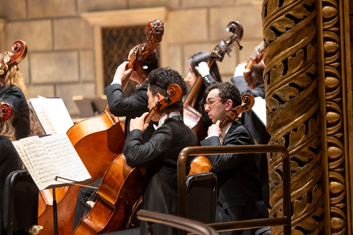Orchestra members performing in a concert hall at the University of Rochester's Eastman School of Music.