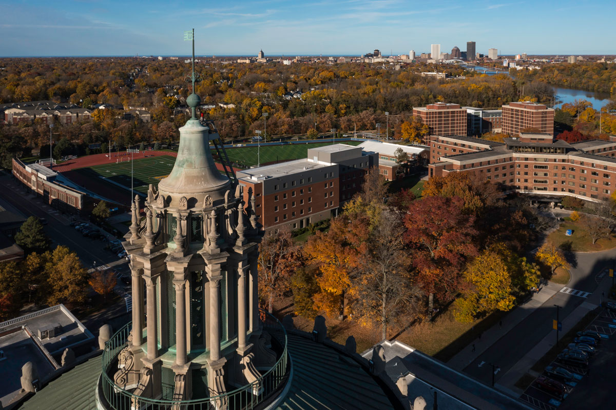 Aerial view of the University of Rochester campus showcasing its buildings and green spaces against a clear sky.